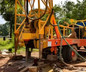 A drilling rig in action shows borewell drilling services & flushing a hole on a construction site.
