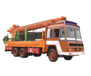 A huge orange truck prepared for borewell drilling services, equipped with a crane on a top of it.
